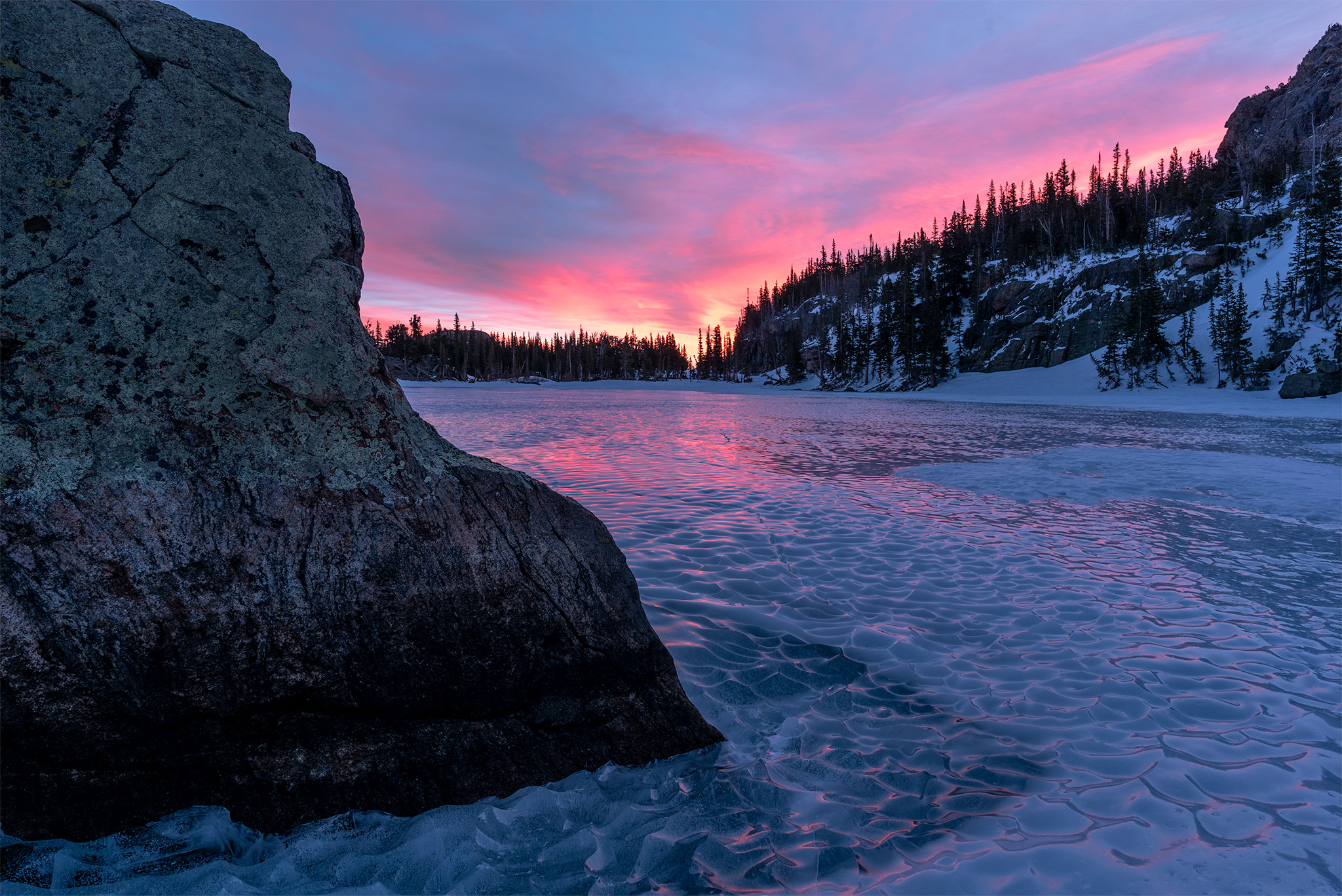 Peaking sunrise looking north at the Loch Vale in Rocky Mountain National Park, frozen apline lake