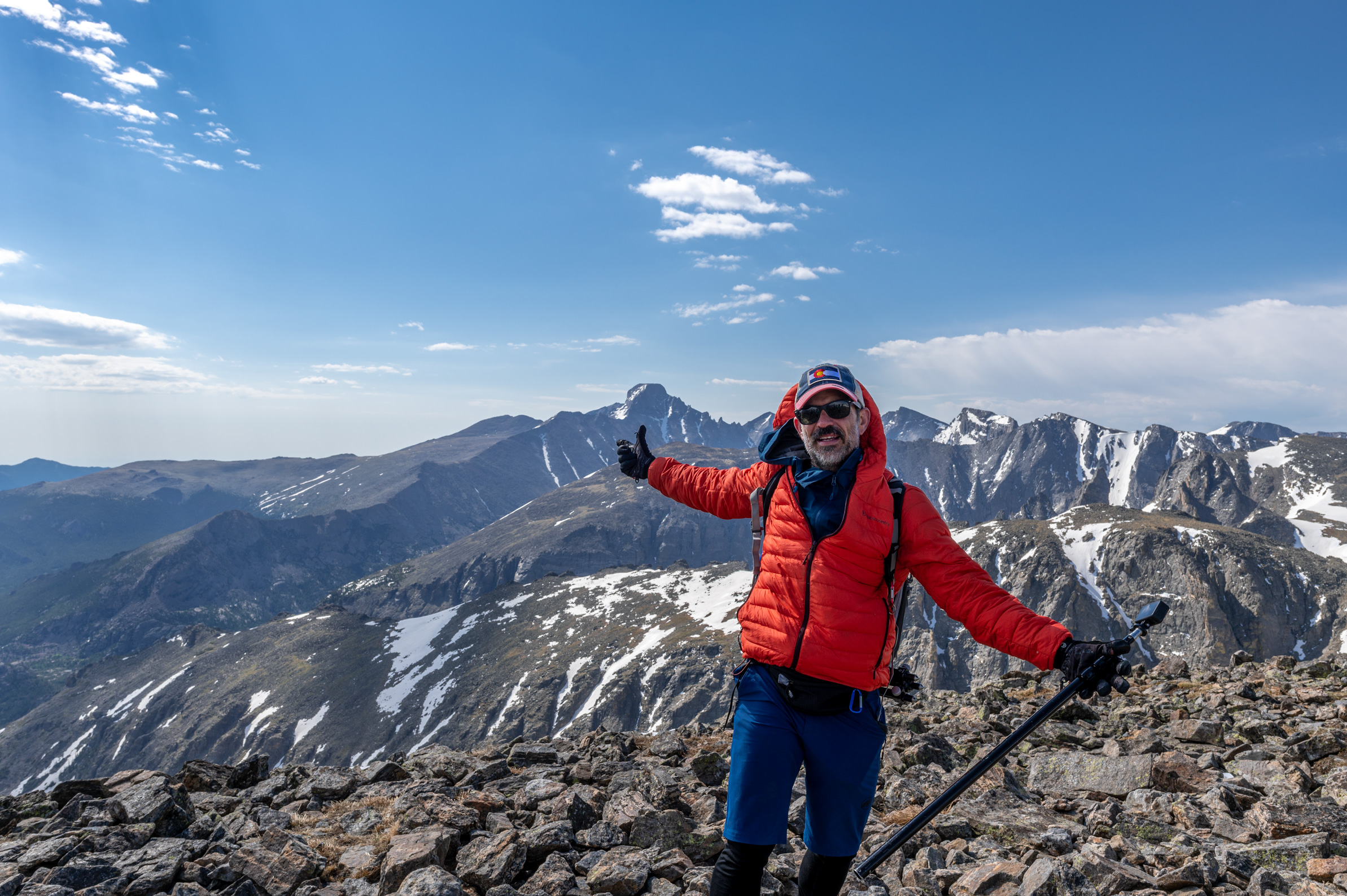 Hiker on the summit of hallett peak holding a gopro