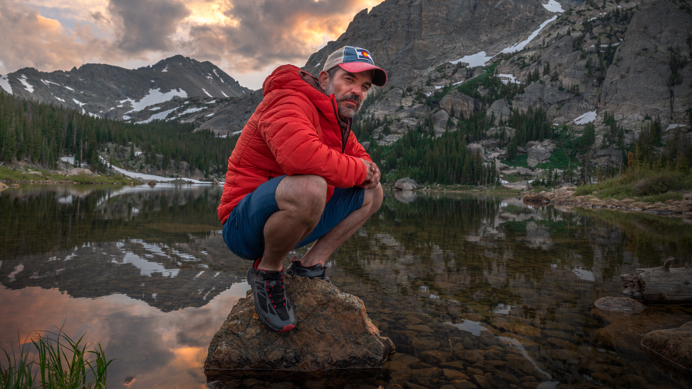 Dave Spates squatting on a rock in Pear Lake, Rocky Mountain National Park Colorado USA during sunset