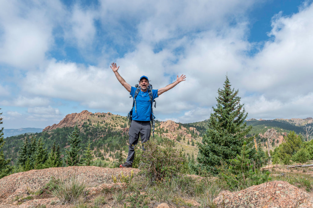 Backpacker with hands up looking at camera in the Lost Creek Wilderness of Colorado