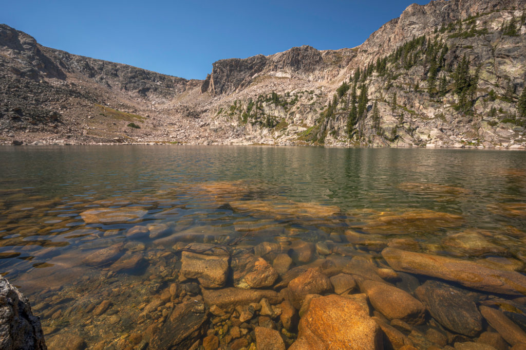 Shallow rocky shore of snowdrift lake in rocky mountain national park